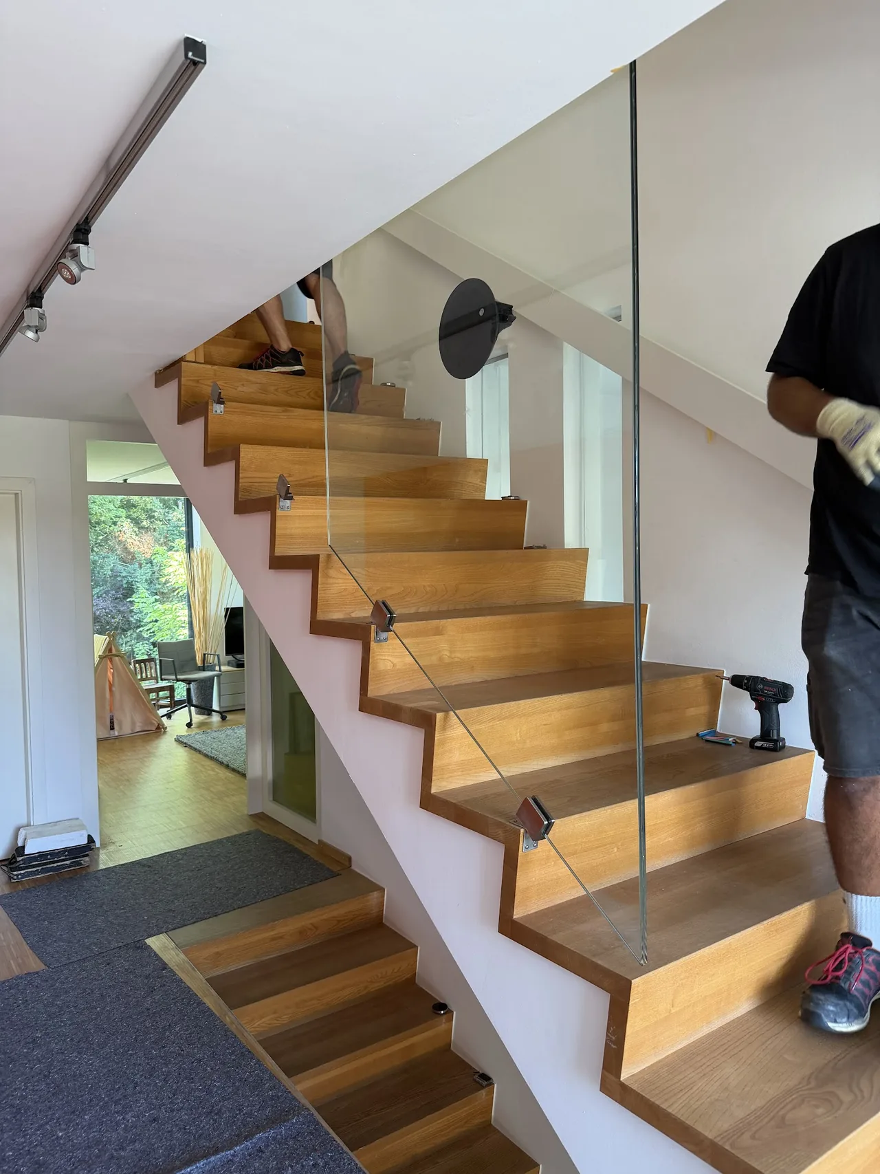 Monteur der Glaserei Kulnork setzt ein Glasgeländer an einer Holztreppe in einem Düsseldorfer Wohnhaus