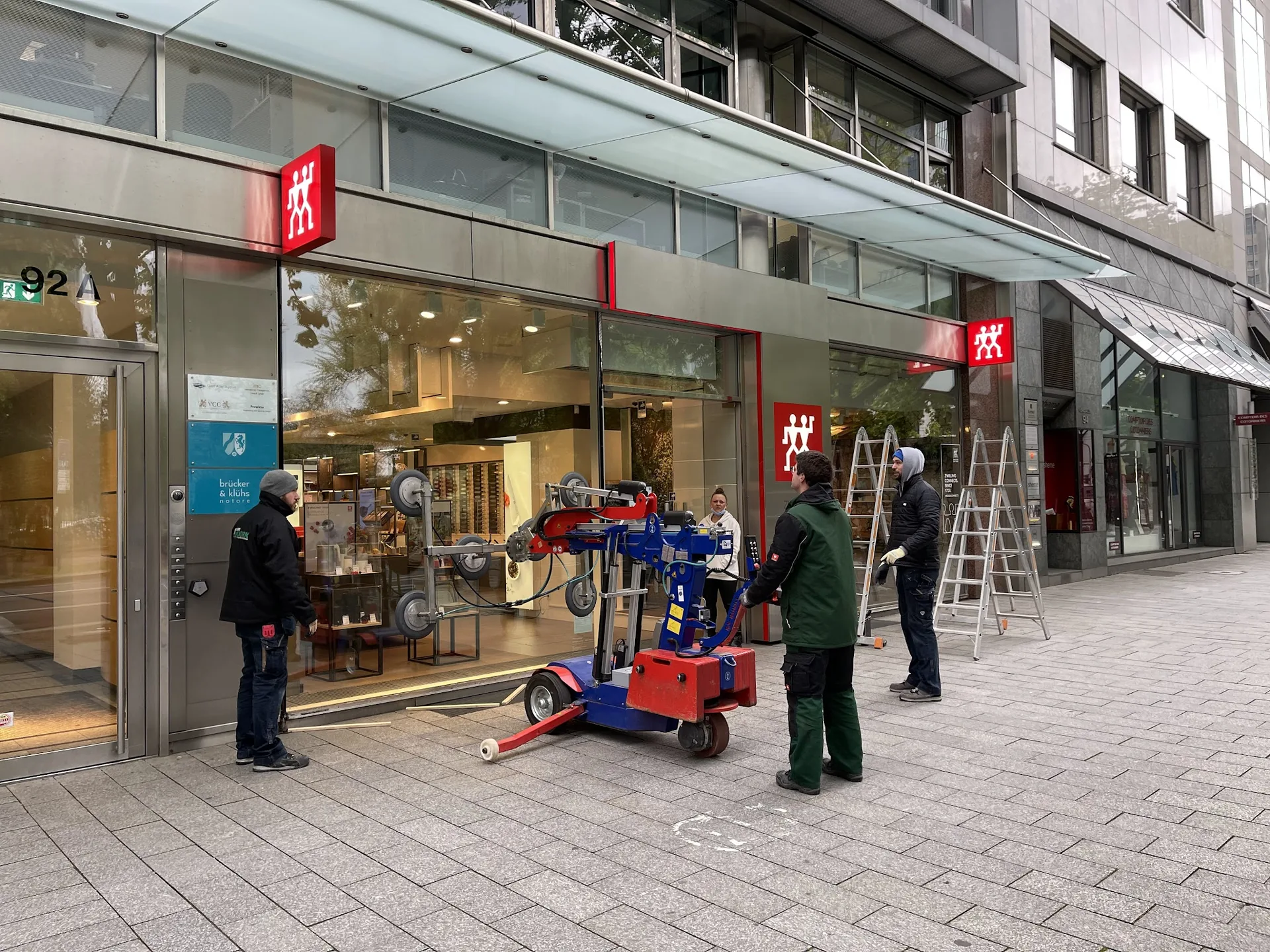 Glaser der Glaserei Kulnork transportieren eine große Scheibe mit dem Glastransportwagen zu einer Ladenfront